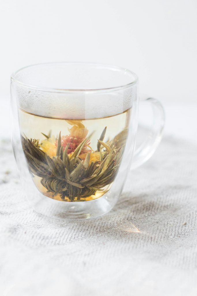 A blooming flowering tea unfurling in a clear glass mug, representing the Functional Wellness category