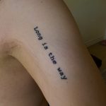 Close up of Lauren's arm tattoo quoting John Milton's Paradise Lost — Long is the way and hard that out of Hell leads up to light